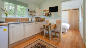 A compact kitchen with a dining area, a TV mounted on the wall, and a bed in the adjacent room. - 1 Bed in Laddingford (oc-s45858) (Laddingford)