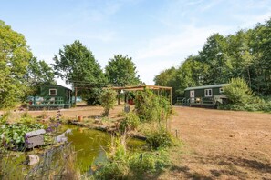 A rustic outdoor area with a pond, wooden structures, and greenery. - 1 Bed in Laddingford (oc-s45858) (Laddingford)