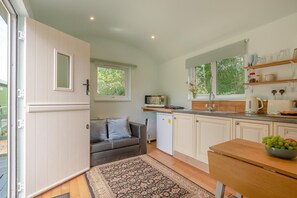 Eine kompakte Küche mit Einbauofen, Spüle und kleinem Kühlschrank.