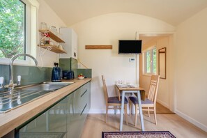 A compact kitchen with a built-in sink, a dining area with a table and chairs, and a TV mounted on the wall. - 1 Bed in Laddingford (oc-s45859) (Laddingford)
