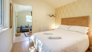 A bedroom with a large bed, a wooden headboard, and a patterned wallpaper. - 1 Bed in Laddingford (oc-s45859) (Laddingford)