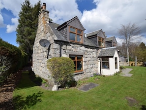 Ein Steinhaus mit geneigtem Dach, einer Satellitenschüssel und einem kleinen Garten.