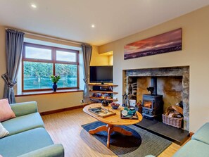 Ein Wohnzimmer mit Kamin, Fernseher und Seeblick.