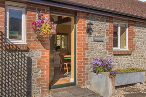 A brick house with a stone exterior, a wooden door, and a window with a hanging flower basket. - 1 Bed in Boys Hill (oc-b45932) (Boys Hill)