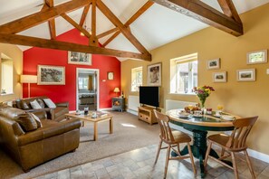 Una sala de estar acogedora con una pared roja, un sofá de cuero marrón, una mesa de comedor de madera con sillas y una chimenea.