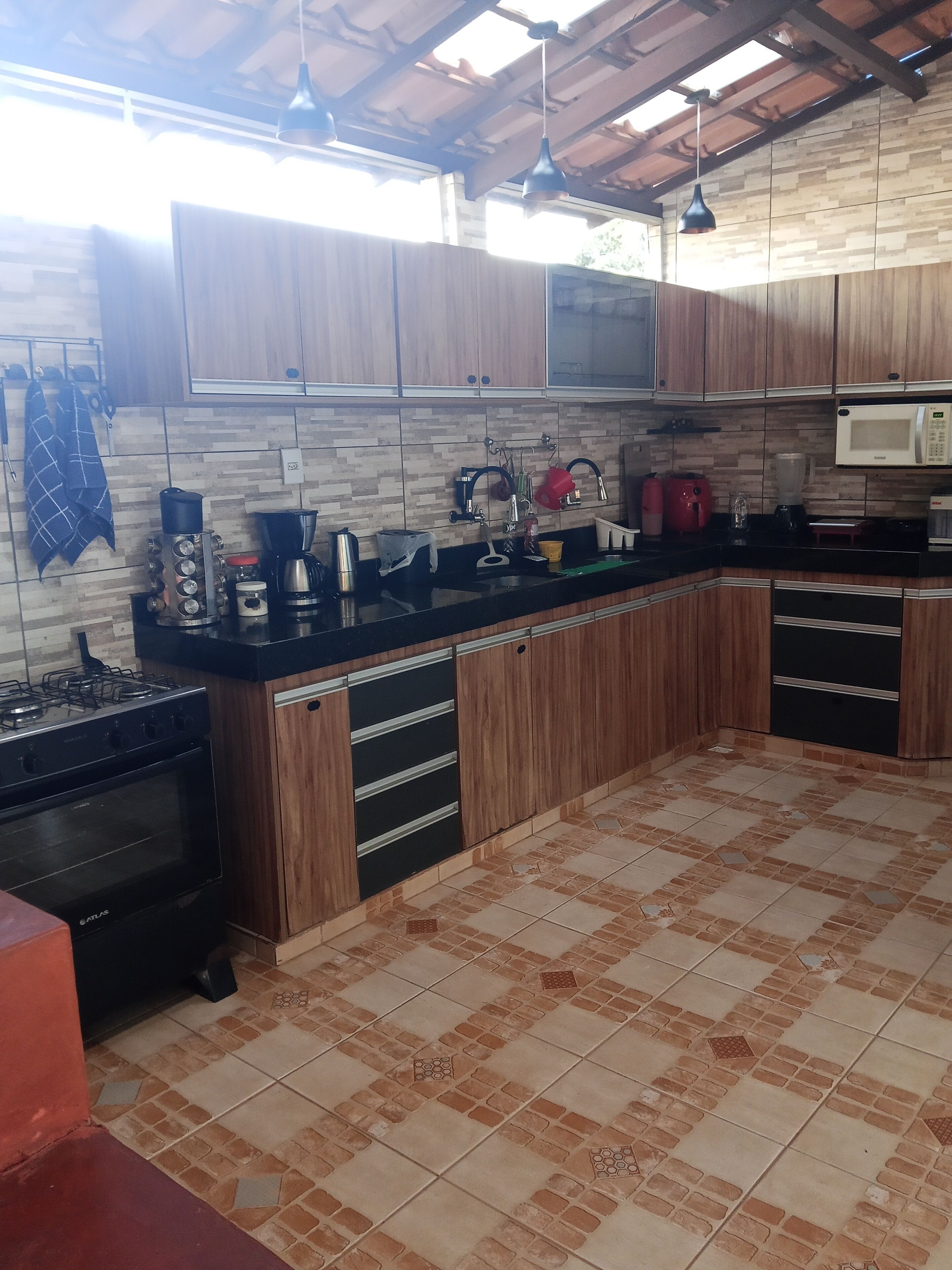 A kitchen with wooden cabinets, a gas stove, a microwave, and a tiled floor.
