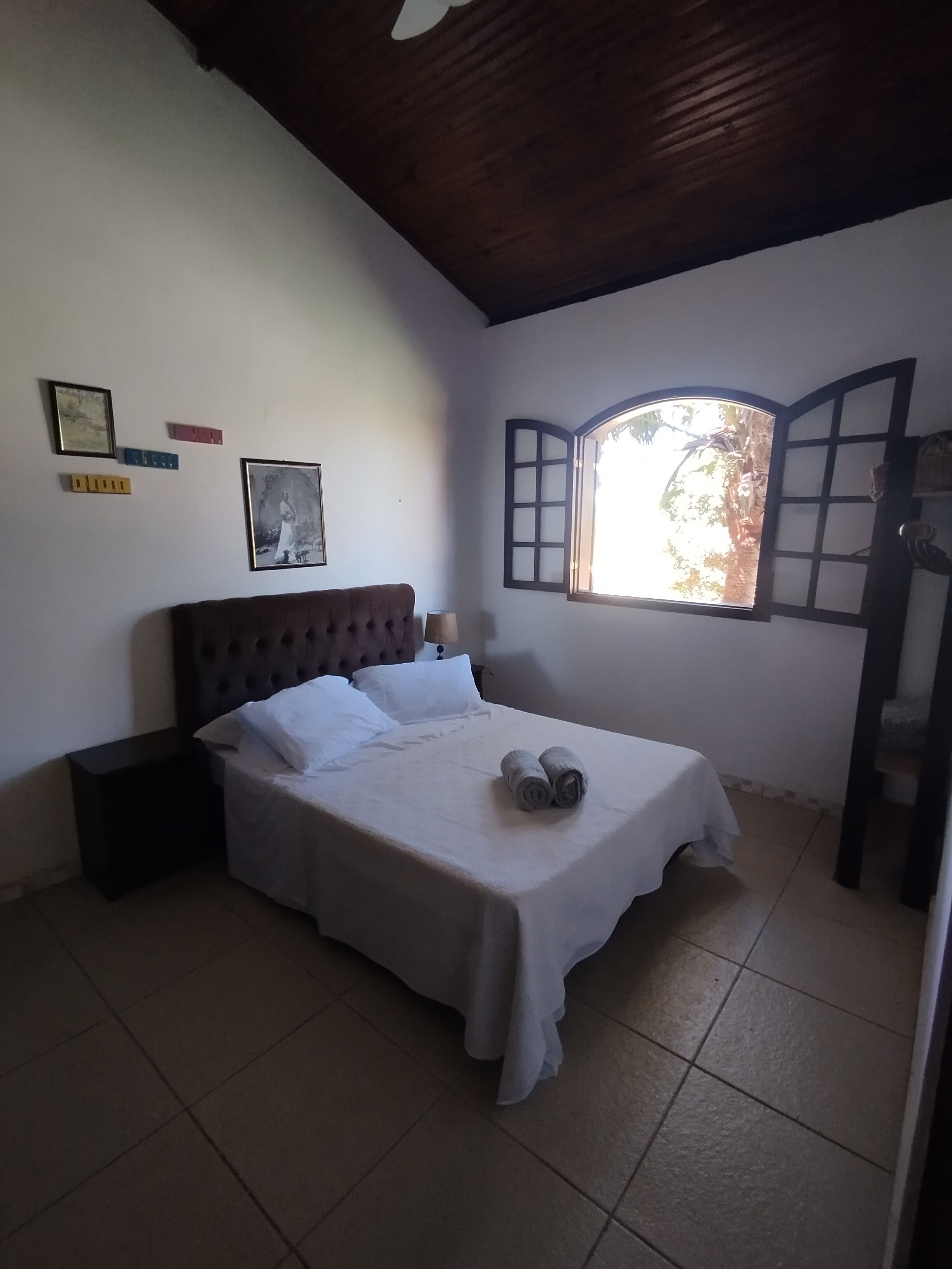 A bedroom with a bed, a nightstand, a window with a view, and wall decorations.