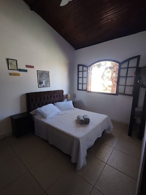 A bedroom with a bed, a nightstand, a window with a view, and wall decorations.