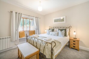 A bedroom with a bed, bedside tables, a window with curtains, a radiator, and a wall-mounted picture. - 1 Bed in Grasmere (oc-lr250) (Grasmere)