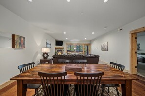 A dining area with a wooden table and chairs, a fireplace, and a television on the wall.