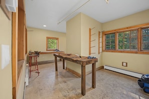 A room with a large wooden table, a window with a view of greenery, and a ladder leaning against the wall. - Trillium Lake Condo 302 at South Grand Lodge | Tree-Lined Balcony Views (Government Camp)