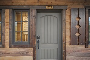 A wooden house with a gray door, a window with blinds, and a number '302' above the door.
