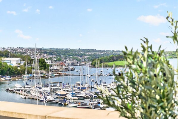 A marina with multiple boats docked, a clear sky, and a distant view of a town. - 3 Bed in Falmouth (oc-b673665) (Flushing)