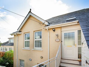 Ein zweistöckiges Haus mit einer weißen Tür, einem kleinen Fenster und einer sichtbaren Treppe.