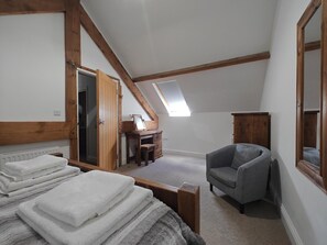 A bedroom with a sloped ceiling, a wooden desk, a chair, and a bed with folded towels. - 4 Bed in Colyton (oc-b45892) (Colyton)