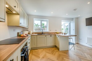 A modern kitchen with wooden countertops, a built-in oven, and a window providing natural light. - 4 Bed in Seahouses (oc-h45933) (Seahouses)