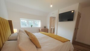 A bedroom with a bed, a window, a bedside table, a TV, and a door. - 4 Bed in Seahouses (oc-h45933) (Seahouses)