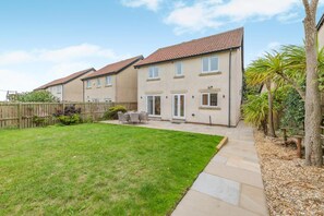 A residential property with a well-maintained lawn, a patio area with outdoor furniture, and a wooden fence. - 4 Bed in Seahouses (oc-h45933) (Seahouses)