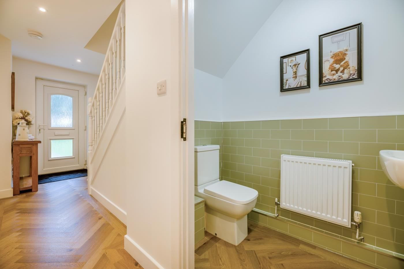 A modern bathroom with a toilet, radiator, and two framed pictures on the wall.