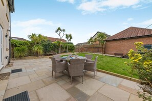 A patio area with a table and chairs, surrounded by a brick wall and a wooden fence. - 4 Bed in Seahouses (oc-h45933) (Seahouses)