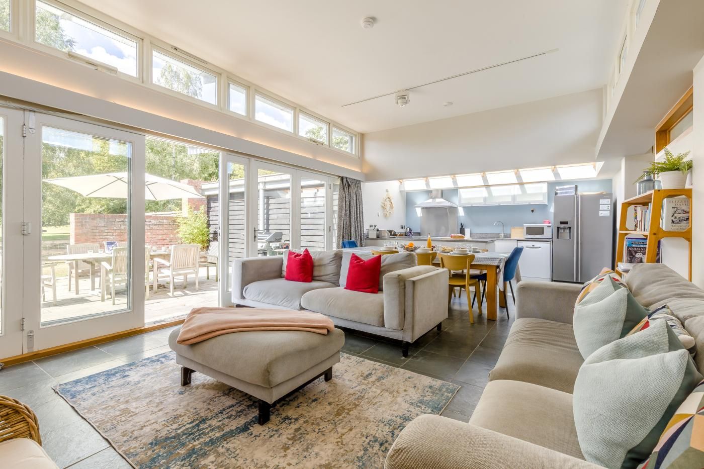 A spacious living area with a sofa set, a dining table, and a kitchen in the background.