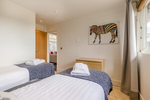 A hotel room with two beds, a wooden headboard, a zebra artwork on the wall, and a window with curtains. - 3 Bed in Cranmer (oc-g45793) (Cranmer)