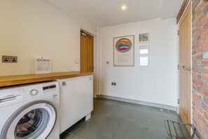 A laundry area with a Bosch washing machine, a wooden countertop, and a brick wall. - 3 Bed in Cranmer (oc-g45793) (Cranmer)