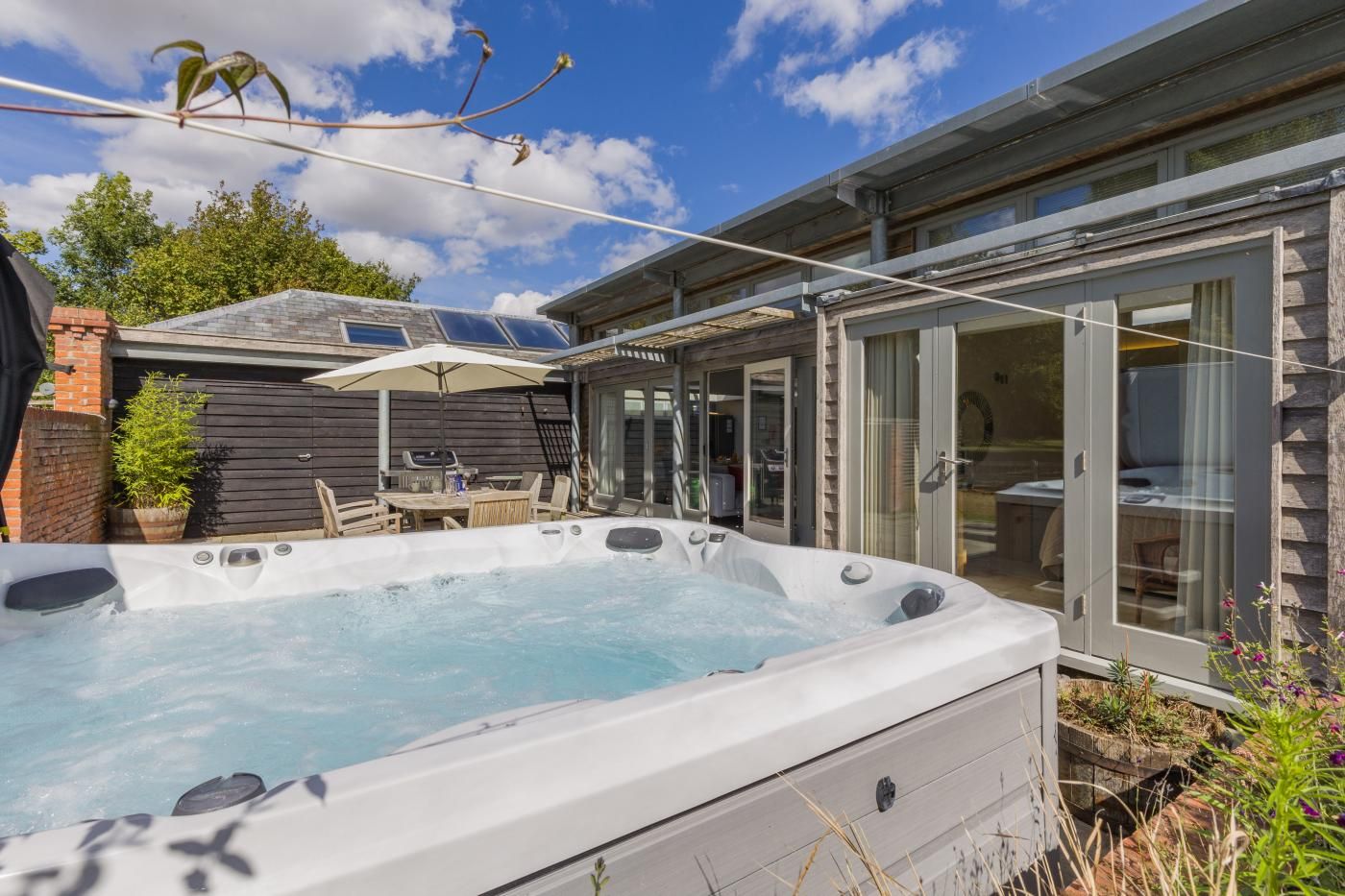 Un jacuzzi con mesa y sillas, un patio cubierto y una valla de madera.