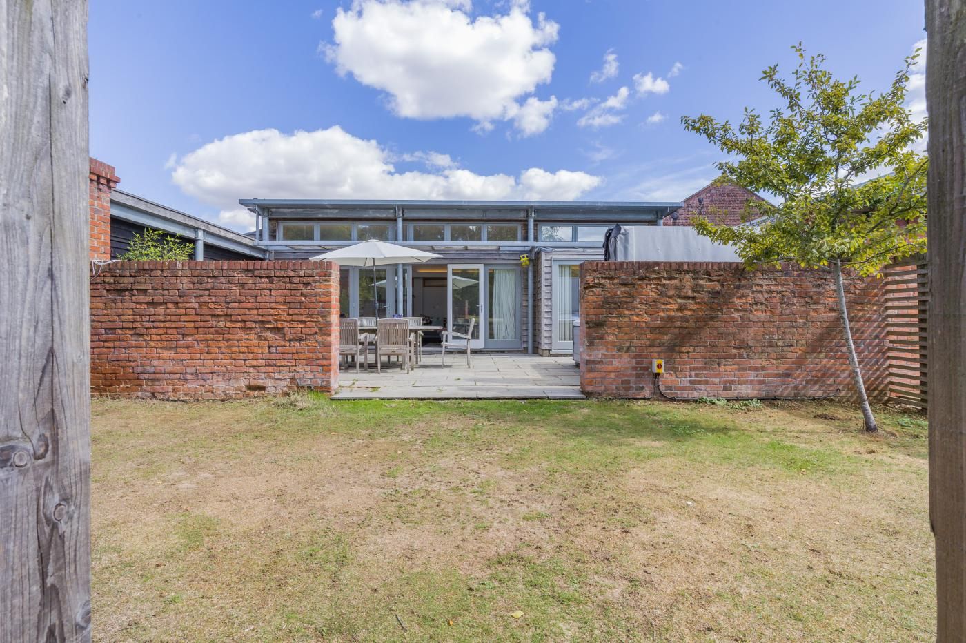 A modern house with a brick exterior, a glass door entrance, and a patio area with outdoor furniture.