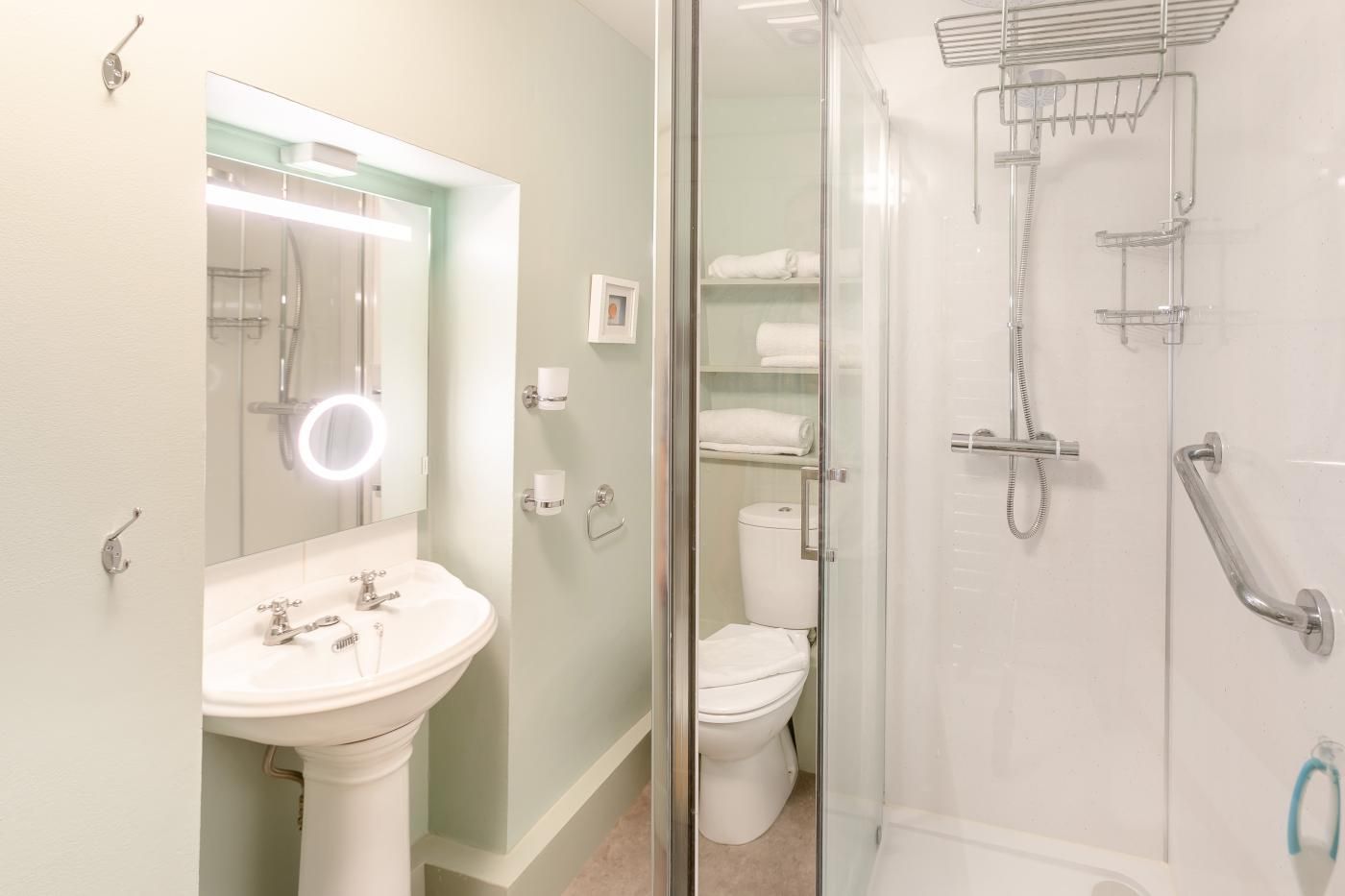 A modern bathroom with a glass shower enclosure, a sink with a mirror, and a toilet.