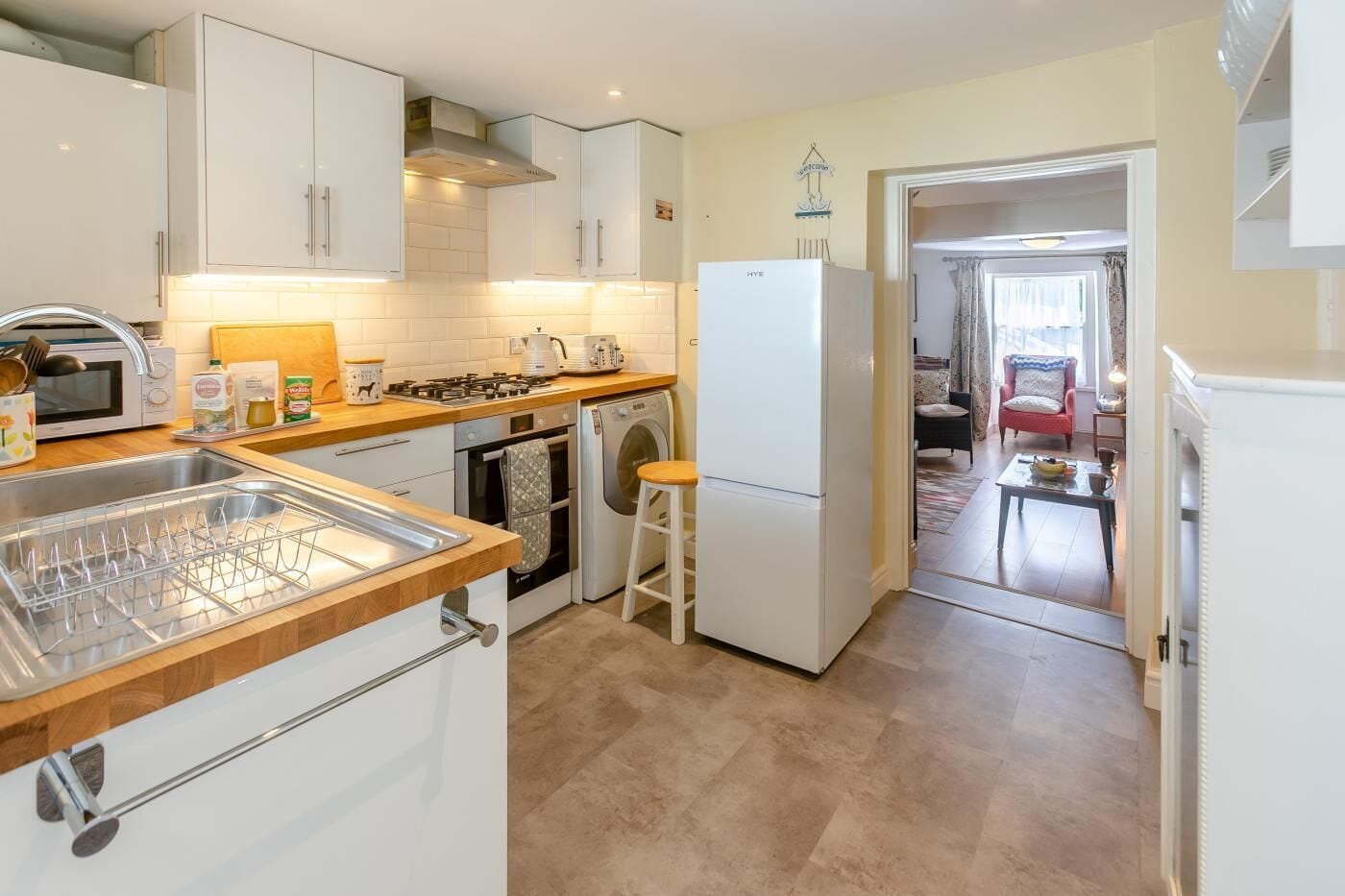A compact kitchen with white cabinets, a microwave, a stove, a washing machine, and a refrigerator.