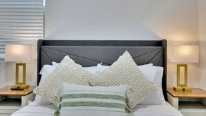 A neatly made bed with a grey headboard, white pillows, and a green and white striped blanket. There are two bedside lamps with gold bases on either side of the bed. - Modern 5B3B｜Near Strip｜Fiber WiFi｜TV in all Rooms (Las Vegas)