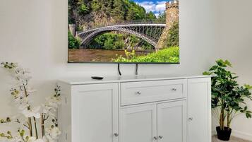 Uma central de entretenimento branca com uma televisão de tela plana montada acima, exibindo uma imagem panorâmica de uma ponte.