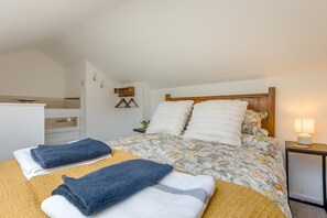 Ein Hotelzimmer mit Bett, Nachttisch mit Lampe, einer Garderobe und einem kleinen Badezimmerbereich.