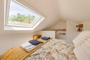 A bedroom with a skylight, a bed with a floral bedspread, a bedside table, and a wardrobe. - 2 Bed in Llanwrthwl (oc-b45319) (Llanwrthwl)