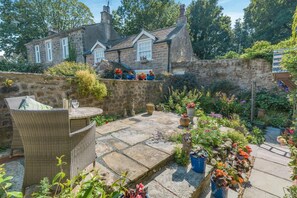 A stone house with a garden patio, stone walls, and potted plants.