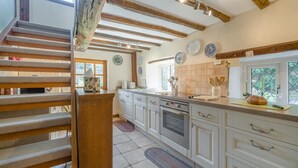 A kitchen with white cabinets, a wooden staircase, and a window with a view. - 1 Bed in Ribchester (oc-n45957) (Ribchester)