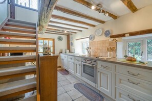 A kitchen with white cabinets, a wooden staircase, and a window with a view. - 1 Bed in Ribchester (oc-n45957) (Ribchester)