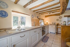 A kitchen with white cabinets, a double sink, and a wooden ceiling.