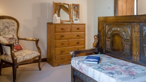 A room with a wooden dresser, a chair with a cushion, and a bed with a floral bedspread. - 1 Bed in Ribchester (oc-n45957) (Ribchester)