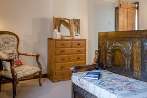 A room with a wooden dresser, a chair with a cushion, and a bed with a floral bedspread. - 1 Bed in Ribchester (oc-n45957) (Ribchester)