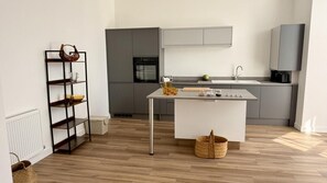 A modern kitchen with a central island, grey cabinets, and a built-in oven. - 3 Bed in Ilfracombe (oc-b45837) (Ilfracombe)