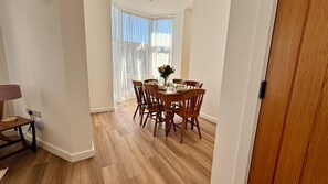A dining area with a round table, six chairs, and a vase with flowers. - 3 Bed in Ilfracombe (oc-b45837) (Ilfracombe)
