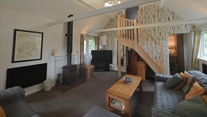 A spacious living room with a fireplace, a wooden staircase, and a cozy sofa. - 2 Bed in Crow (oc-h45921) (Ringwood)
