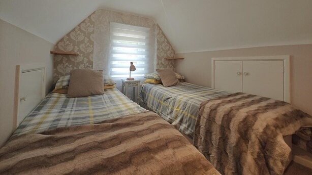 A bedroom with two beds, a window with blinds, a lamp on a side table, and a wardrobe. - 2 Bed in Crow (oc-h45921) (Ringwood)