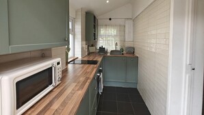 A compact kitchen with a microwave, sink, and cabinets. - 2 Bed in Crow (oc-h45921) (Ringwood)