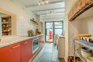 A kitchen with a red and white color scheme, a built-in oven, and a view to the outside. - 3 Bed in Treknow (oc-p45966) (Treknow)