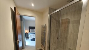 A hotel room with a glass shower enclosure, a bed with a headboard, and a nightstand with a lamp. - 3 Bed in Spittal (oc-b45905) (Spittal)
