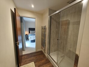 A hotel room with a glass shower enclosure, a bed with a headboard, and a nightstand with a lamp. - 3 Bed in Spittal (oc-b45905) (Spittal)