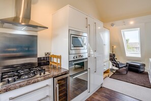 A compact kitchen with a gas stove, oven, microwave, and white cabinetry. - 3 Bed in Spittal (oc-b45905) (Spittal)